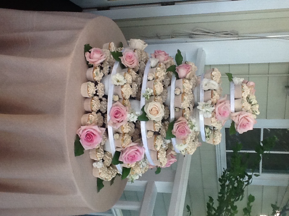 Tiered display of frosted cupcakes with pink and white roses