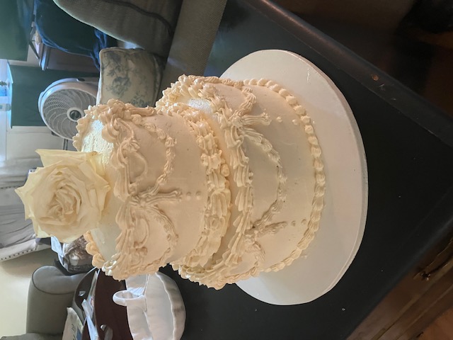 Ornate ivory cake finished with a single white rose